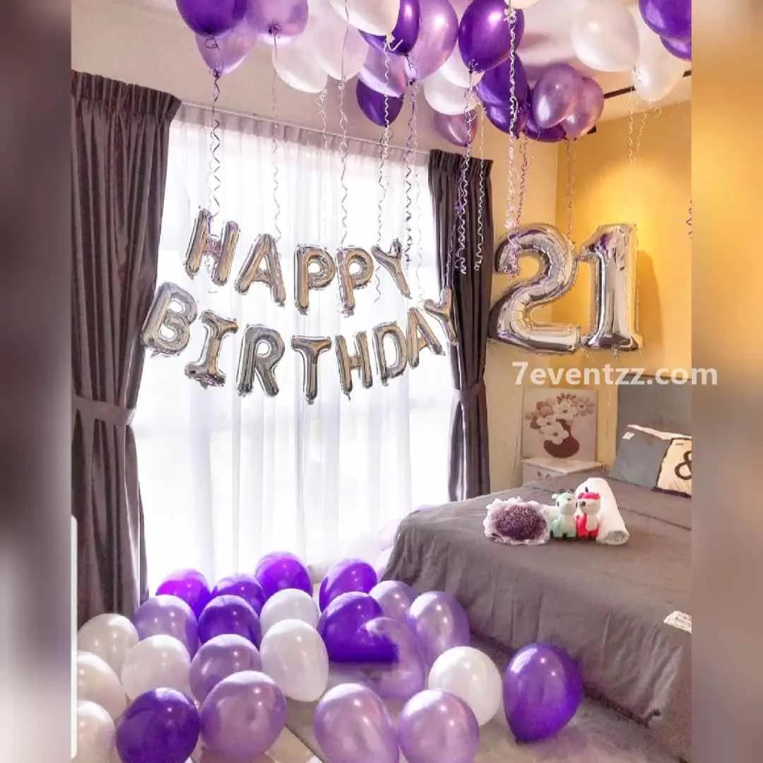 Milestone birthday decoration setup with number foil balloons and colorful balloon backdrop