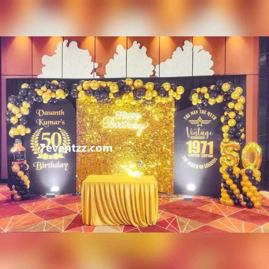 Grand 50th birthday stage setup with large decorative backdrop and balloon columns