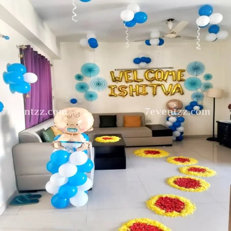 Baby boy home welcome setup with blue and gold balloon arrangement, themed backdrop, and personalized name banner