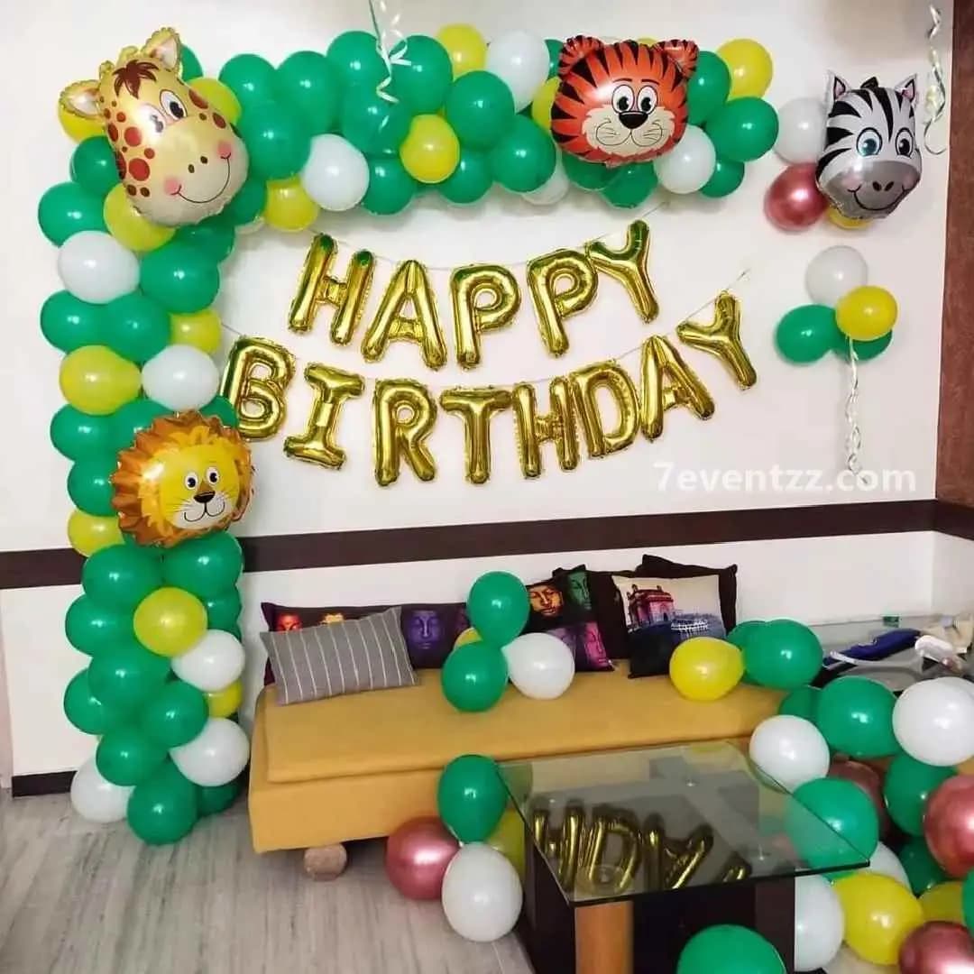 Simple jungle theme birthday decor with green balloon columns and tropical animal cutouts