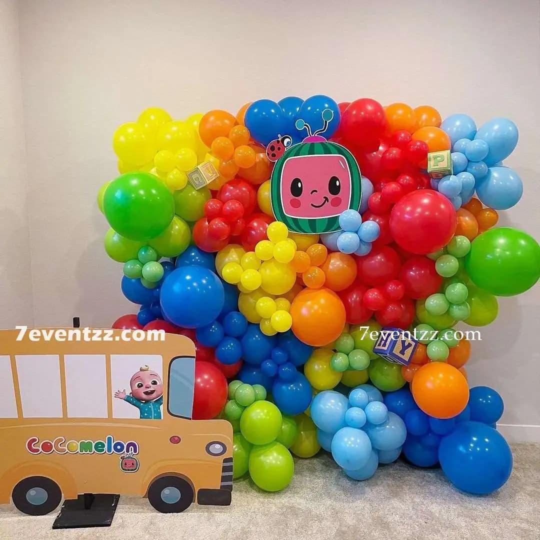 Cocomelon themed wall decoration with character prints, balloons, and colorful streamers for kids birthday