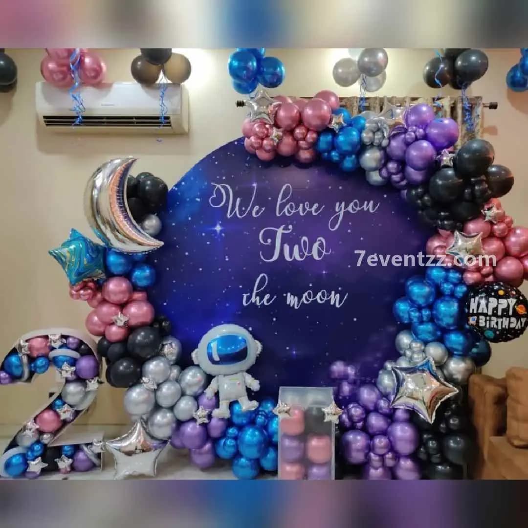Space themed birthday decoration with stars, planets, and rocket balloon arrangement