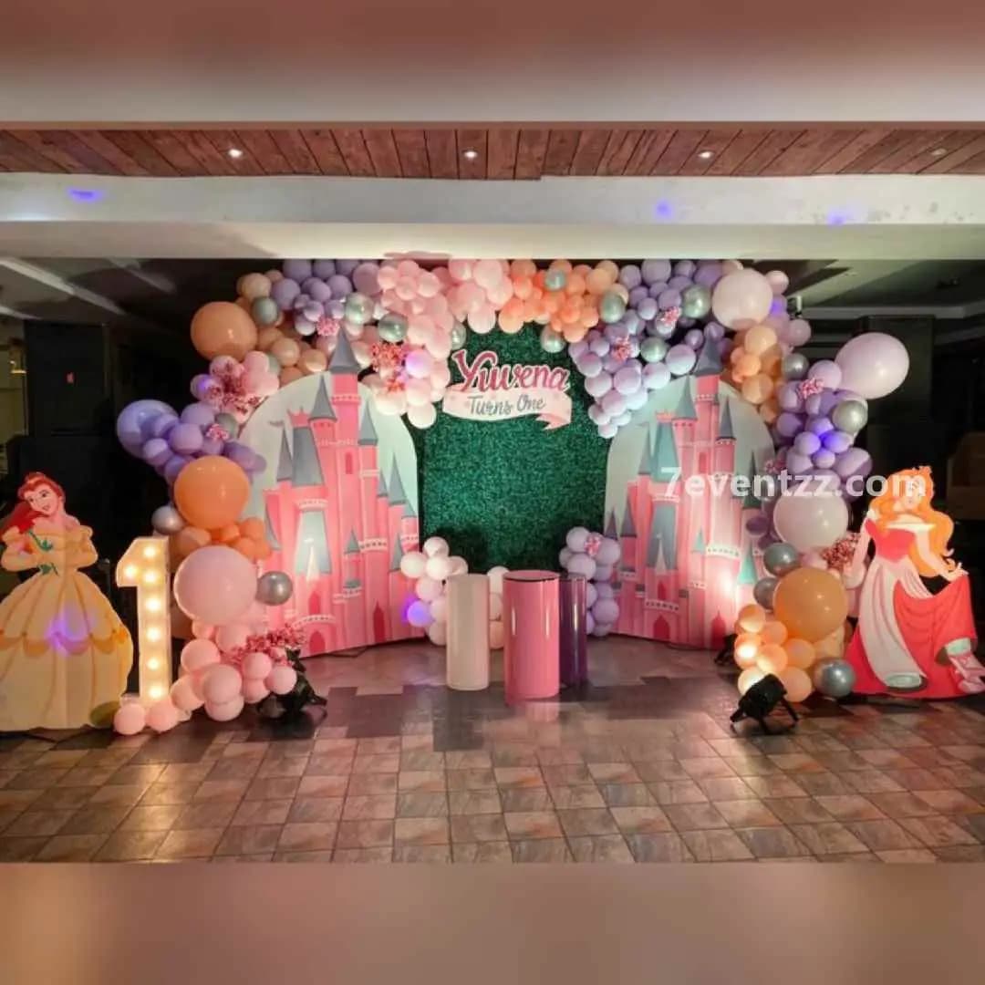 Elaborate Disney Princess themed birthday decoration with grand backdrop, multiple balloon columns, and royal princess props