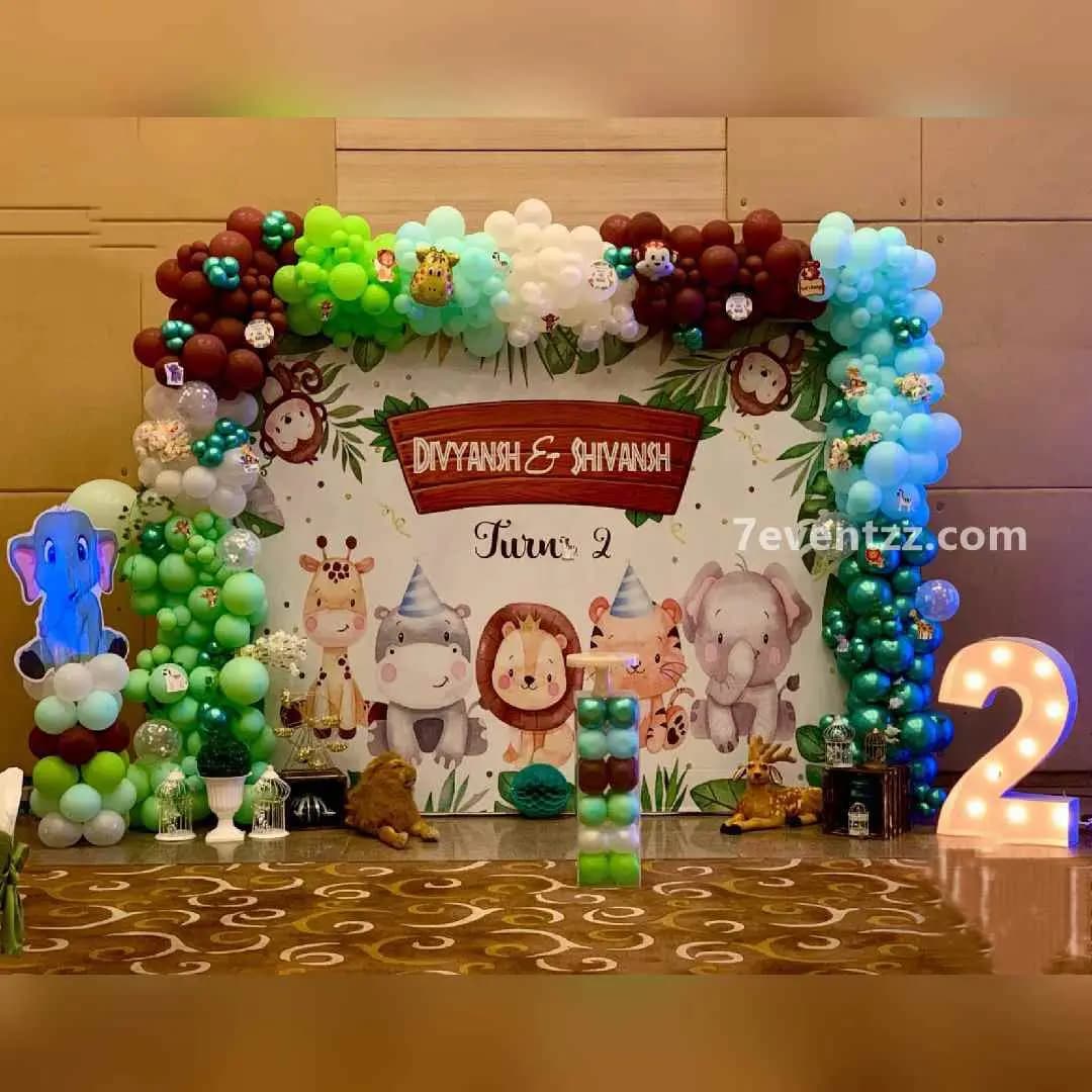 Customized jungle theme birthday setup with personalized backdrop, animal props, and balloon decor