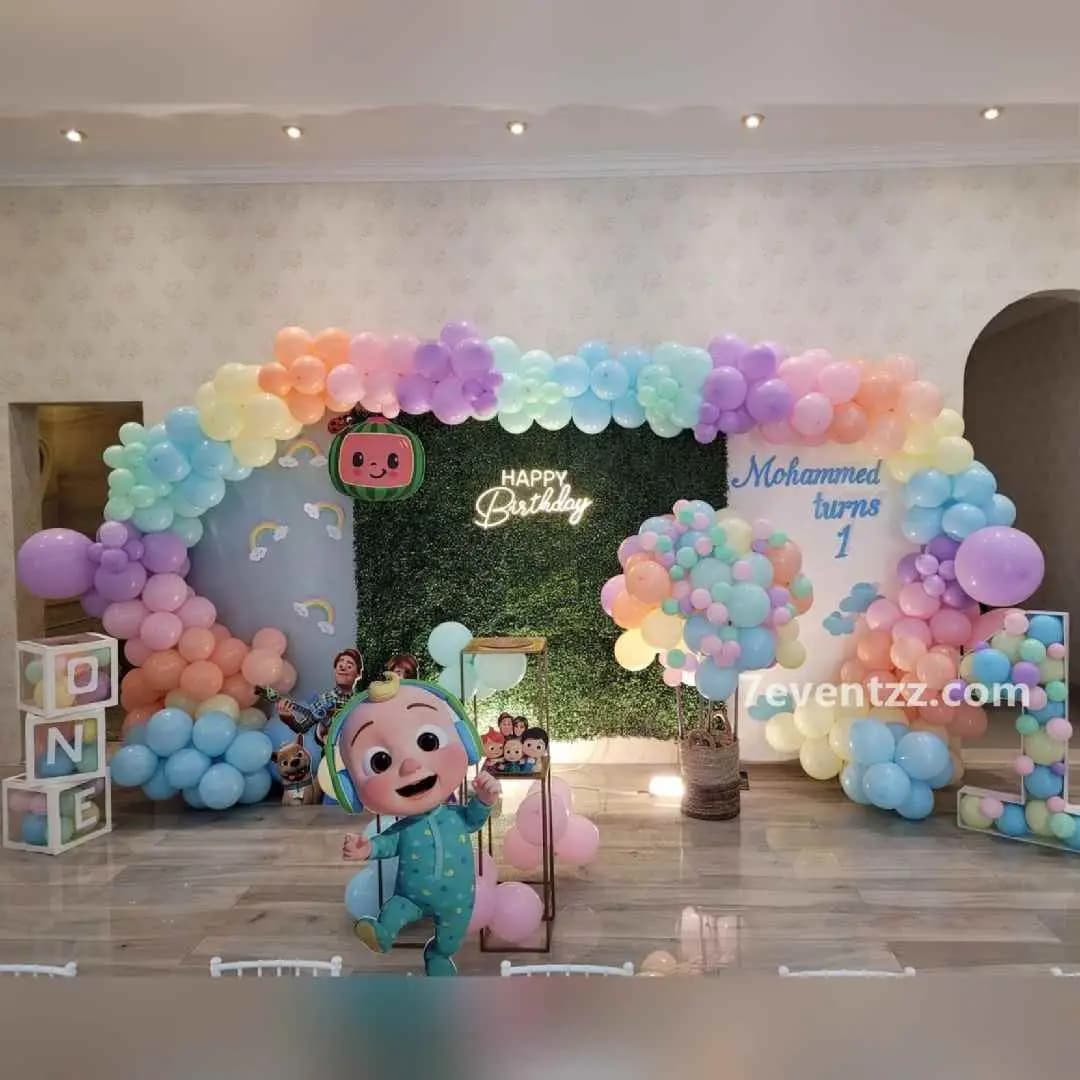 Full Cocomelon themed birthday decoration setup with balloons, backdrop, and character props