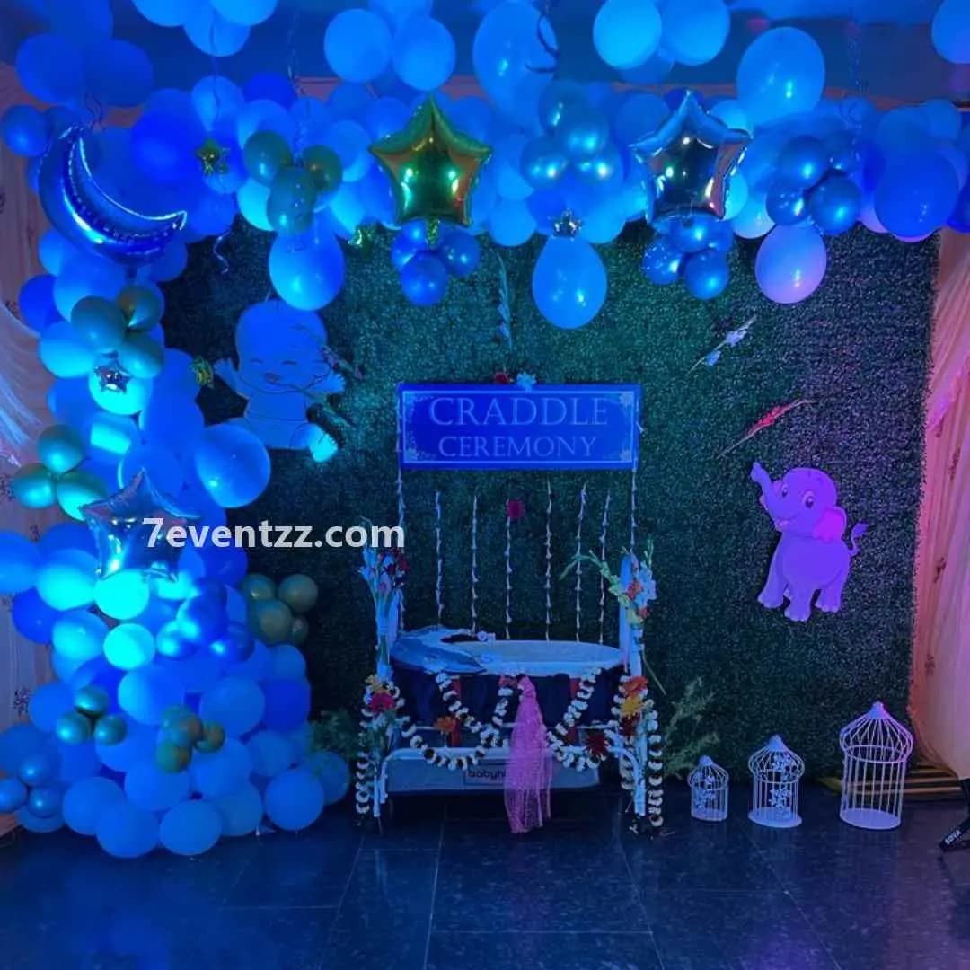 Large decorative backdrop for baby cradle ceremony with floral and balloon styling