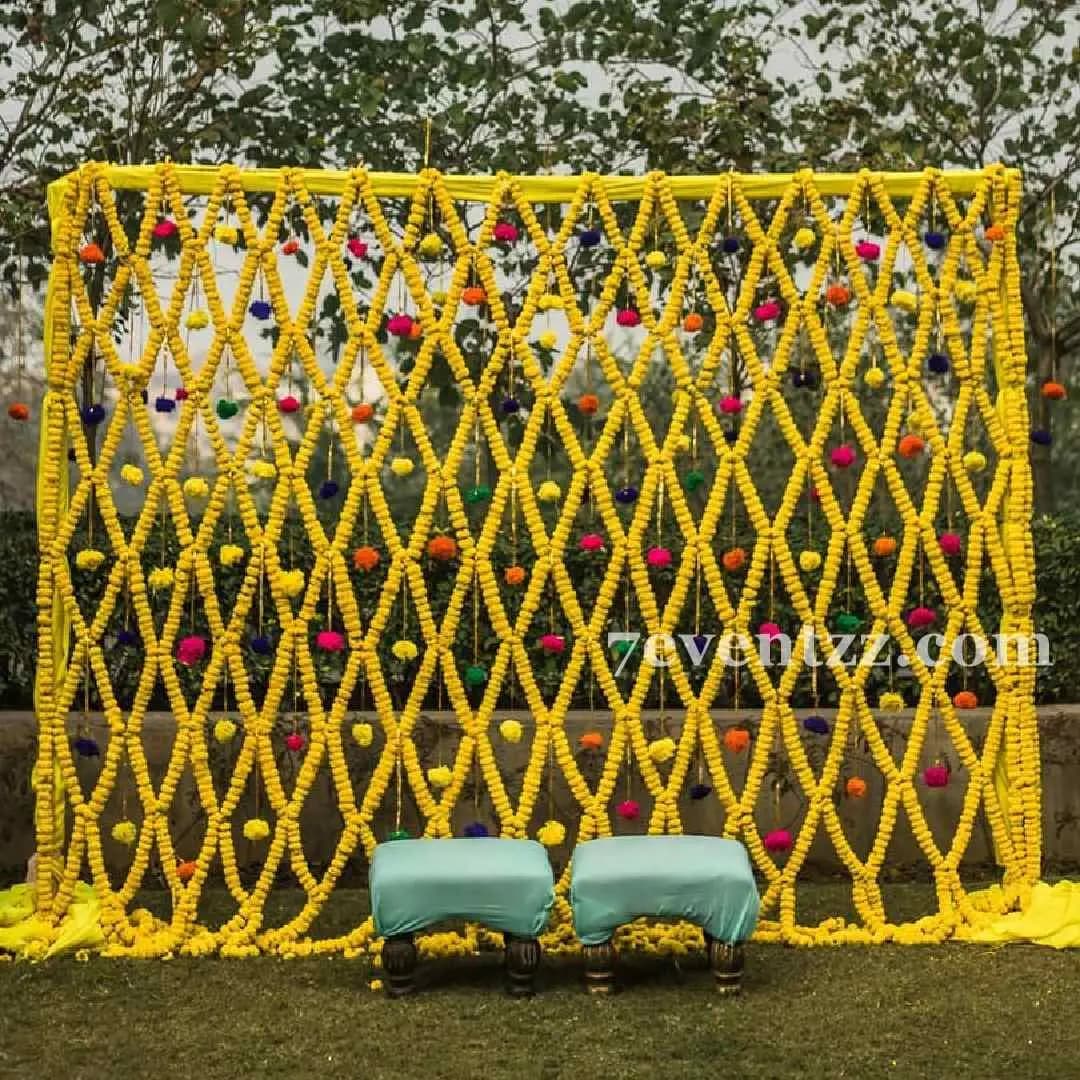 Outdoor haldi decoration with flower arrangements and drapes