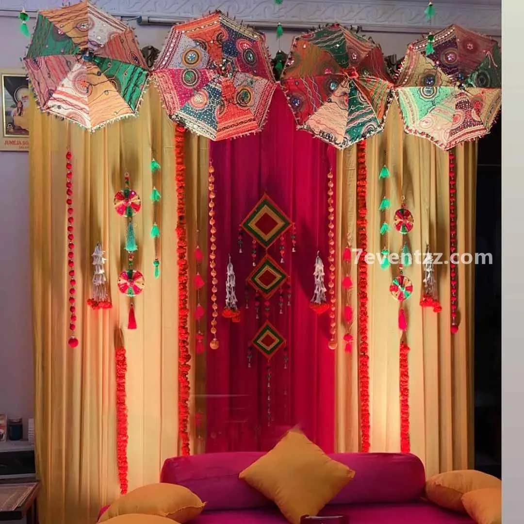 Indoor mehndi decoration with colorful backdrop and floral setup